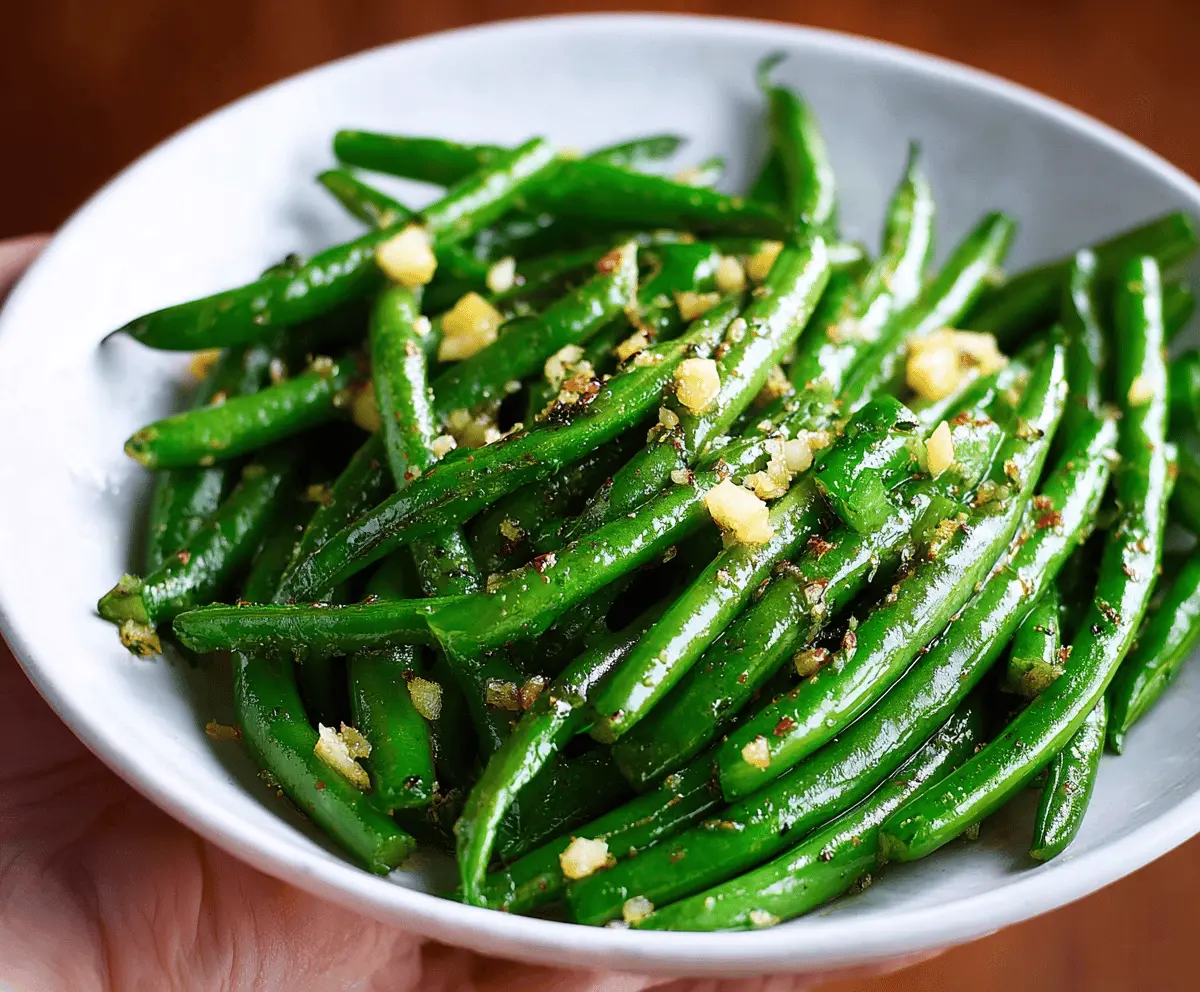Freshly cooked garlic butter green beans garnished with chopped herbs, perfect for a flavorful and healthy side dish.