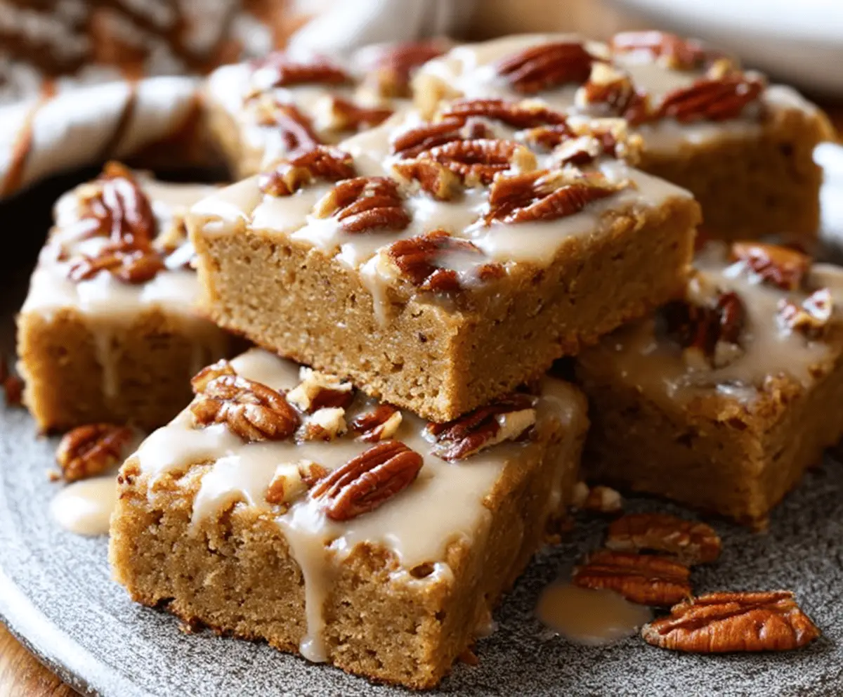 Delicious Maple Pecan Blondies topped with chopped pecans and a drizzle of maple syrup, served on a rustic wooden board