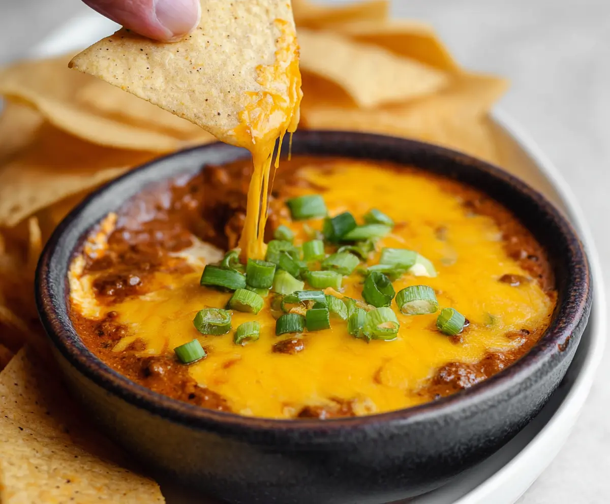 Delicious chili cheese dip with melted cheese and seasoned ground beef served in a bowl, perfect for sharing at parties.