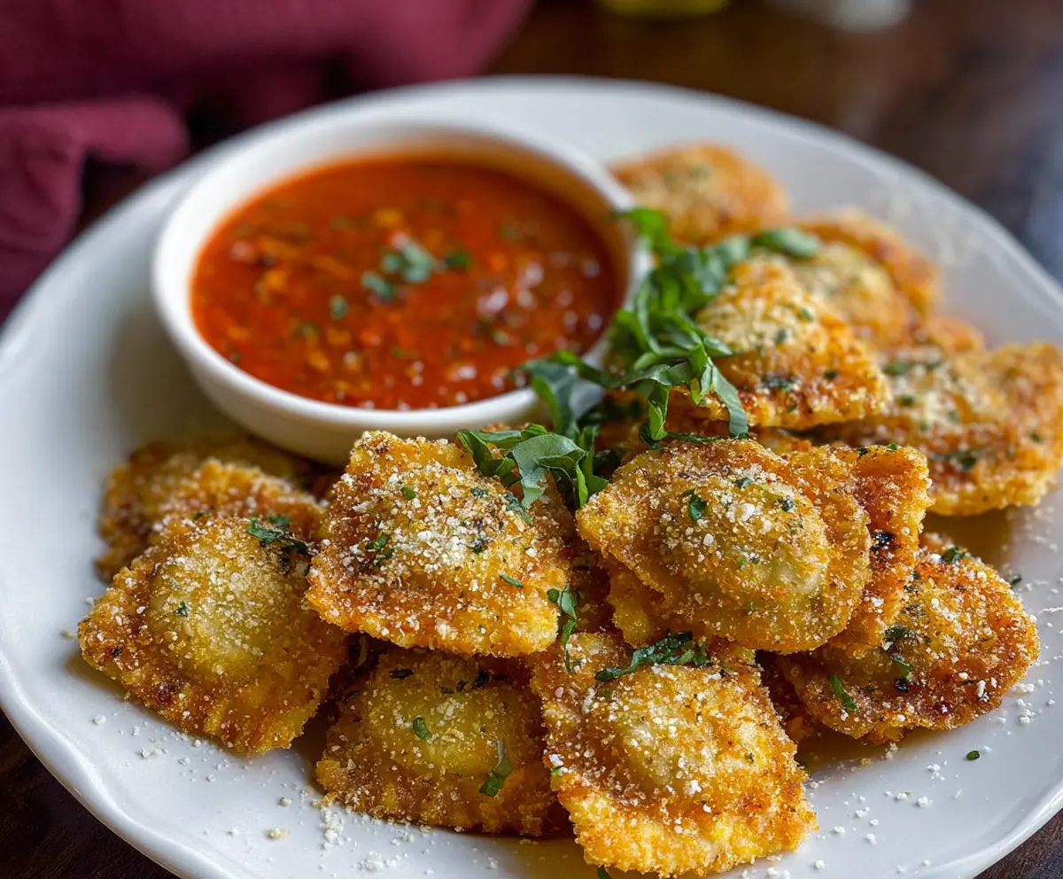 Crispy fried ravioli served with marinara sauce on a white plate