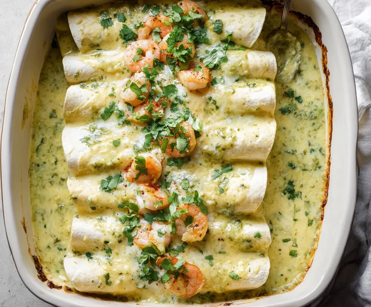 Delicious shrimp enchiladas topped with creamy poblano sauce served on a plate.
