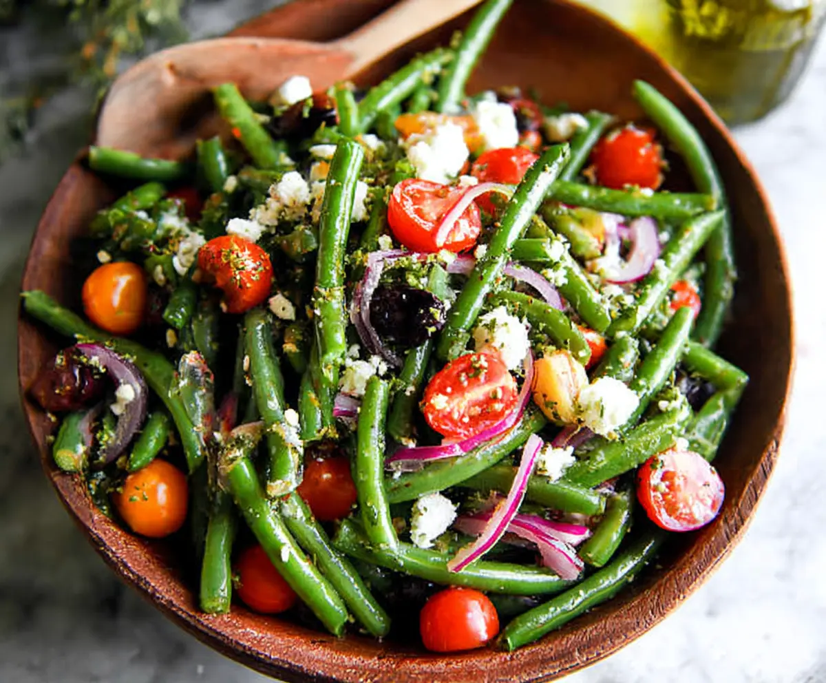 Fresh green bean salad with cherry tomatoes and feta cheese on a white plate