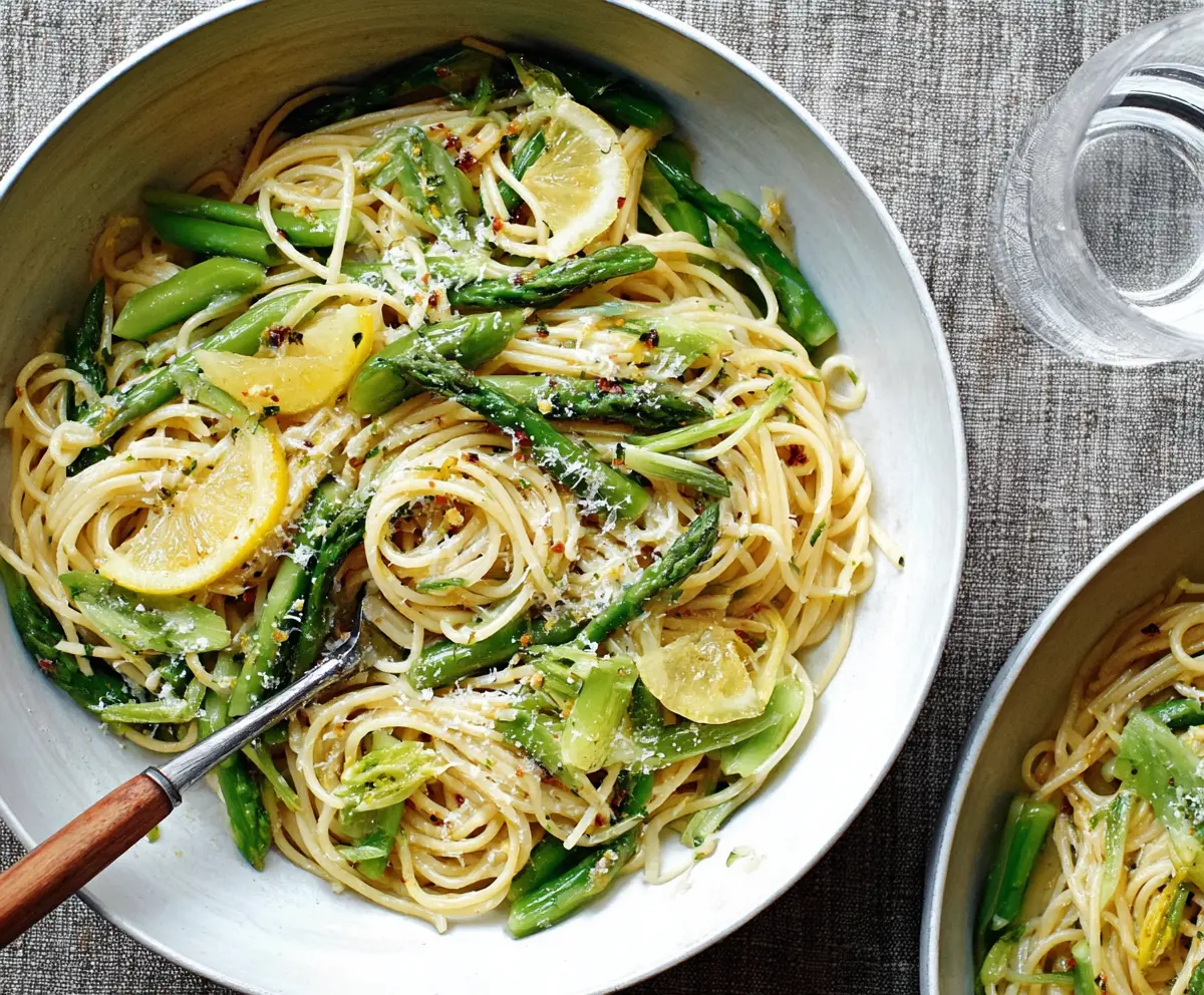 Delicious Lemon Asparagus Pasta on a plate with fresh lemon slices and herbs