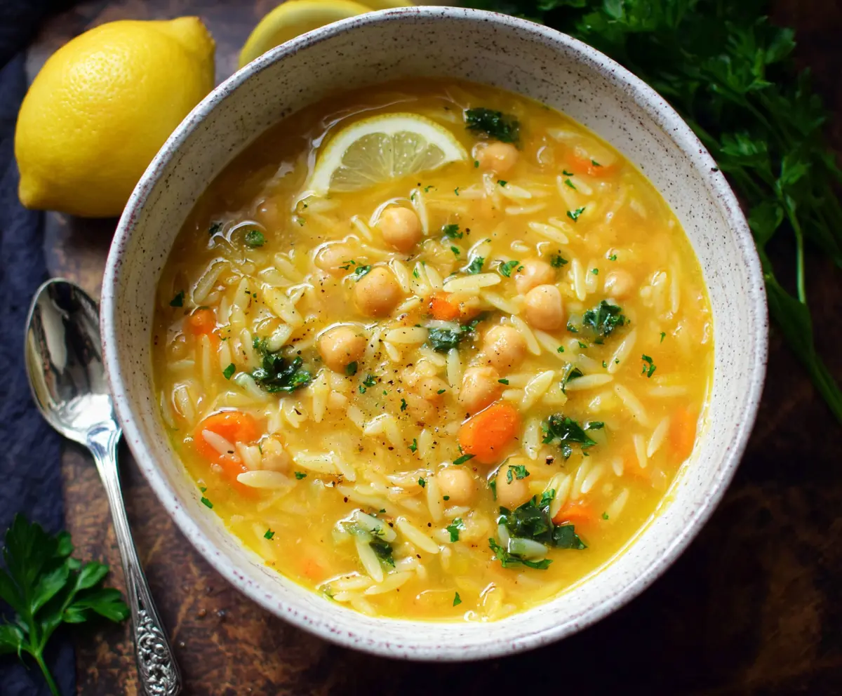 Hearty lemon chickpea orzo soup in a bowl with fresh herbs.