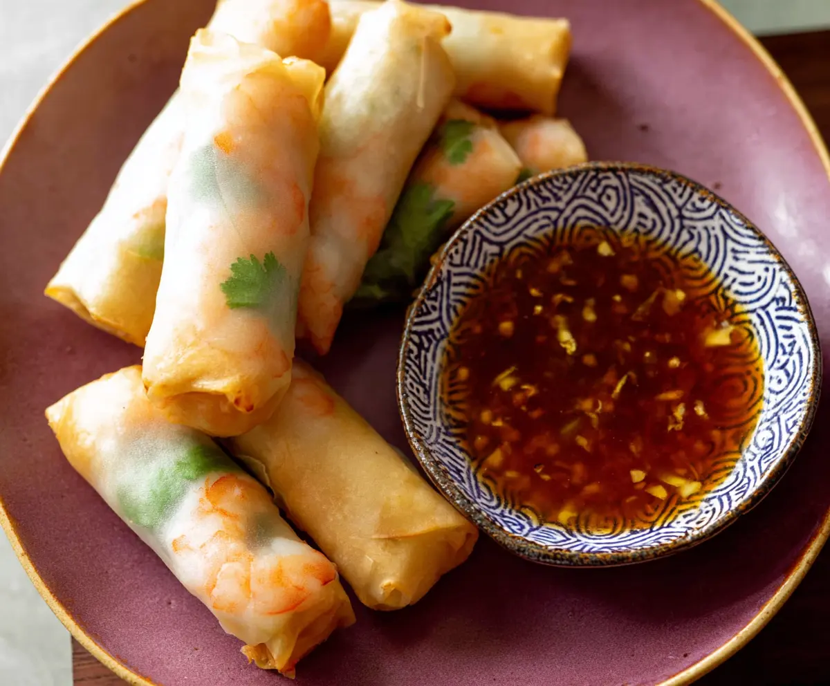 Delicious shrimp and pork spring rolls with fresh vegetables served on a white platter